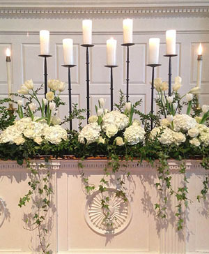 Floral arch decorated with lush white and blush flowers framing a wedding ceremony altar